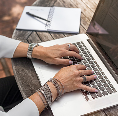 hands of a woman working on a laptop outside